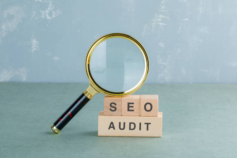Seo analysis and business concept with wooden blocks with words on it, magnifying glass on sage color background side view. horizontal image