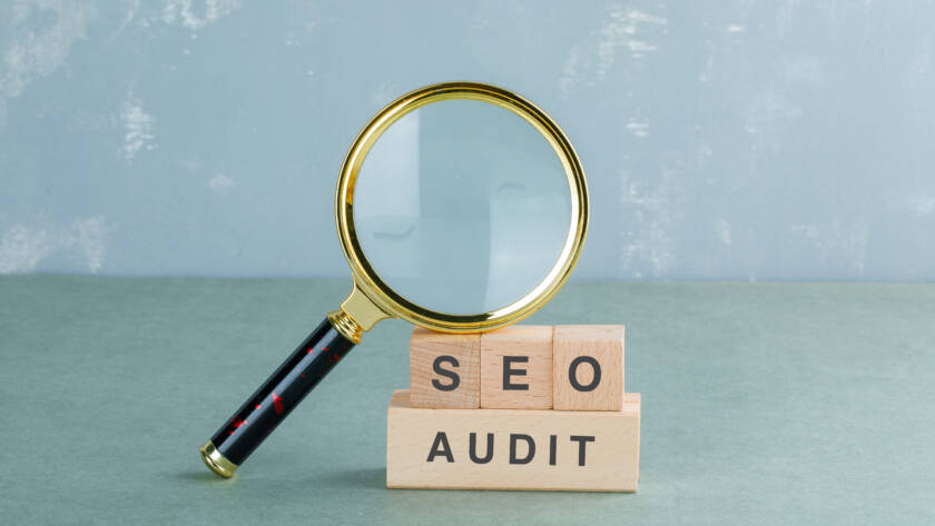 Seo analysis and business concept with wooden blocks with words on it, magnifying glass on sage color background side view. horizontal image