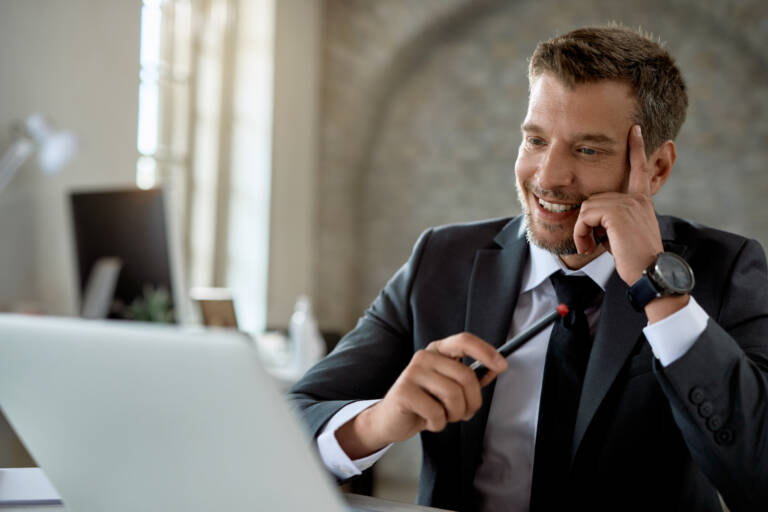 Happy male entrepreneur using laptop while working in the office