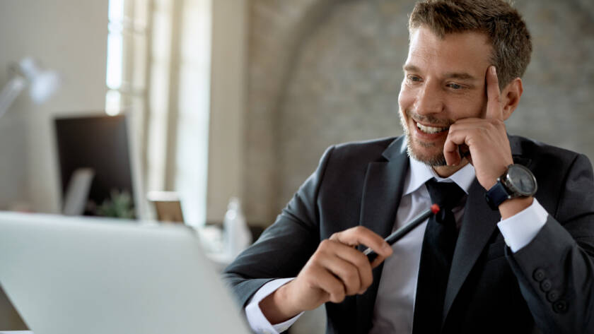 Happy male entrepreneur using laptop while working in the office