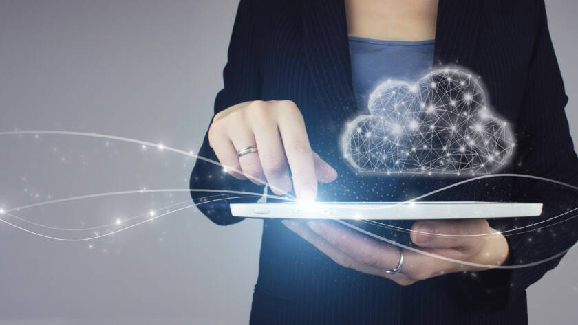 Cloud computing technology internet concept. White tablet in businesswoman hand with digital hologram digital cloud sign on grey background. Communication network.